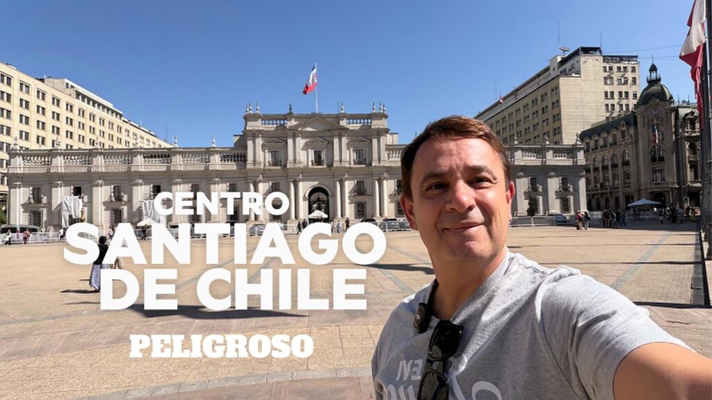 El Palacio de La Moneda en Santiago de Chile en un día soleado, con un viajero en primer plano y texto que advierte sobre la seguridad en el centro de la ciudad.